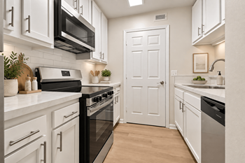 Galley kitchen with white cabinetry and stainless appliances